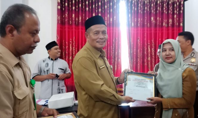 
 Usman A Rachman, SP, SH, MM Asisten Keistimewaan Aceh Ekonomi Pembangunan Setdakab Aceh Timur saat menyerahkan zakat award kepada OPD sebagai pemungut zakat terbaik. Foto Bagian Humas & Protokol Setdakab Aceh Timur.