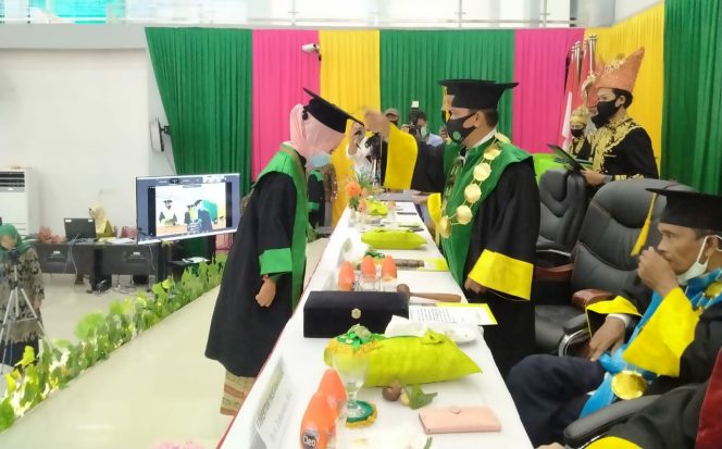 
 Teks : Prosesi pemindahan pita oleh Rektor kepada wisudawati secara simbolis. 