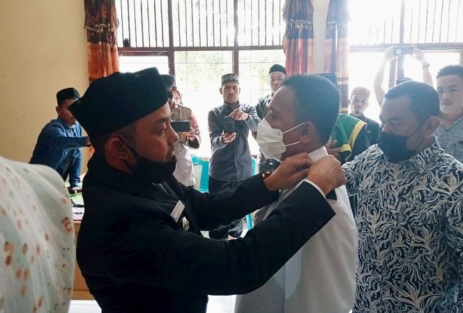 
 Foto : Camat menyematkan tanda jabatan pada Gechik Desa Buket Seulemak pada prosesi pelantikan.