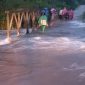 Foto: Warga melintas di jembatan yang terendam banjir.