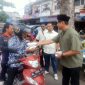 Muhammad Haikal (pakai peci) membagikan nasi kotak kepada pengendara jalan.