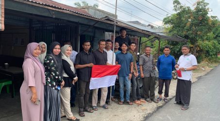 Gechik Mulqan bersama perangkat mensosialisasikan dan membagikan bendera kepada masyarakat.